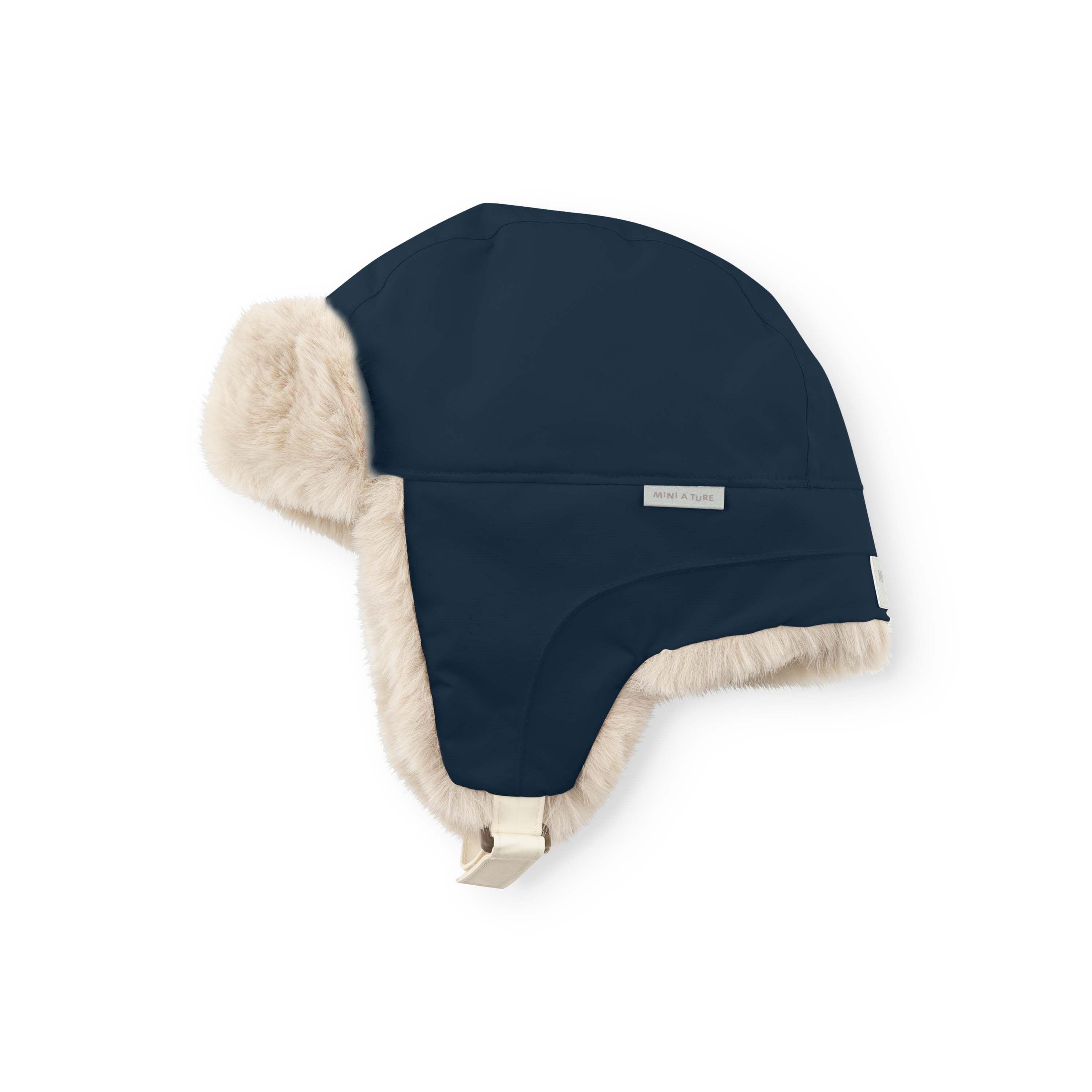 MATCRISTER teddyforet vinterhue i mørk marineblå set fra skrå vinkel med fyldigt, cremefarvet teddyfleece langs øreklapperne og en lys velcrolukning synlig i bunden mod hvid baggrund.