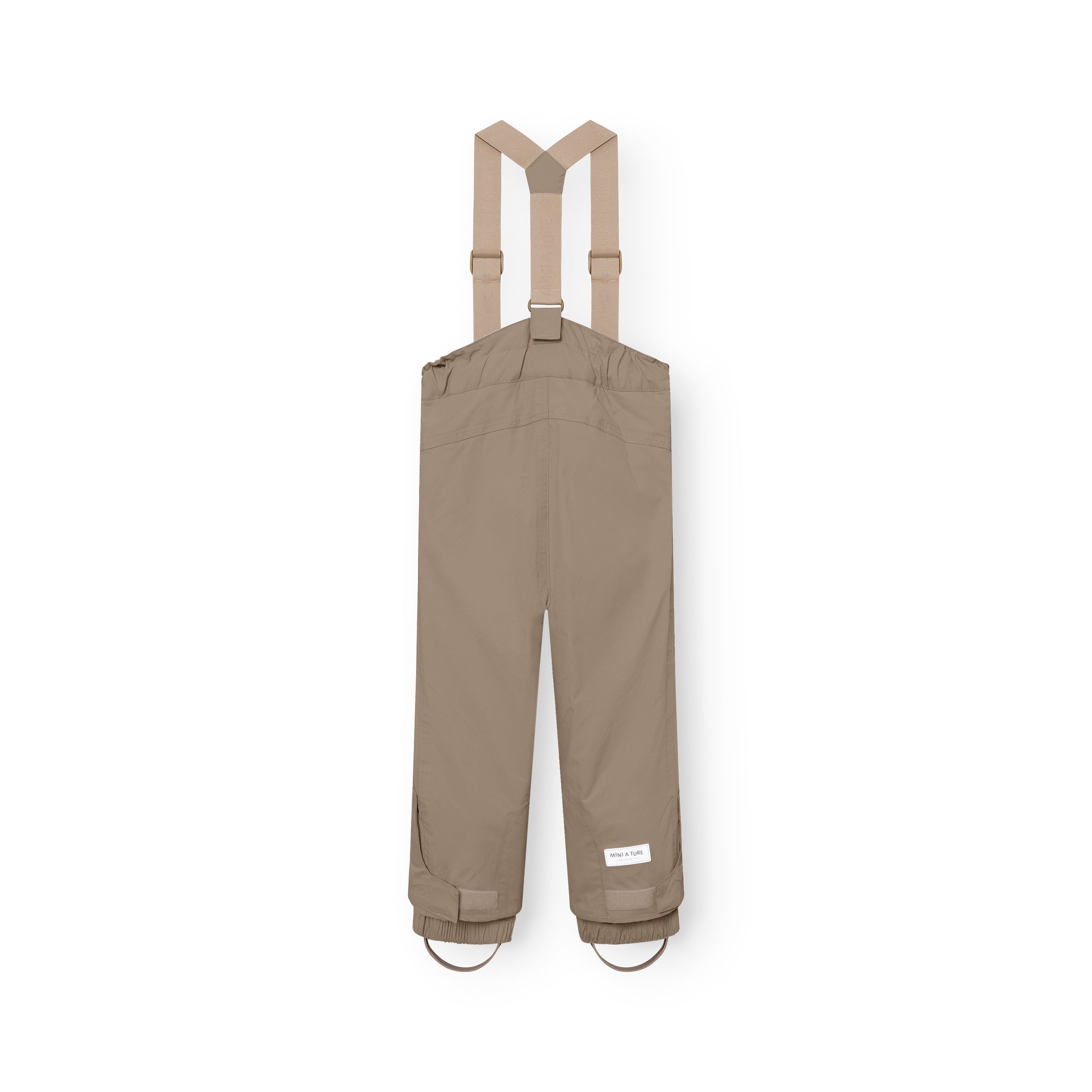 MATWITTE-overtræksbukser i varm beige set bagfra på hvid baggrund med matchende aftagelige seler i Y-form. Bukserne har justerbare glidespænder, elastiske bukseben med fodremme og et MINI A TURE-label på højre bukseben.