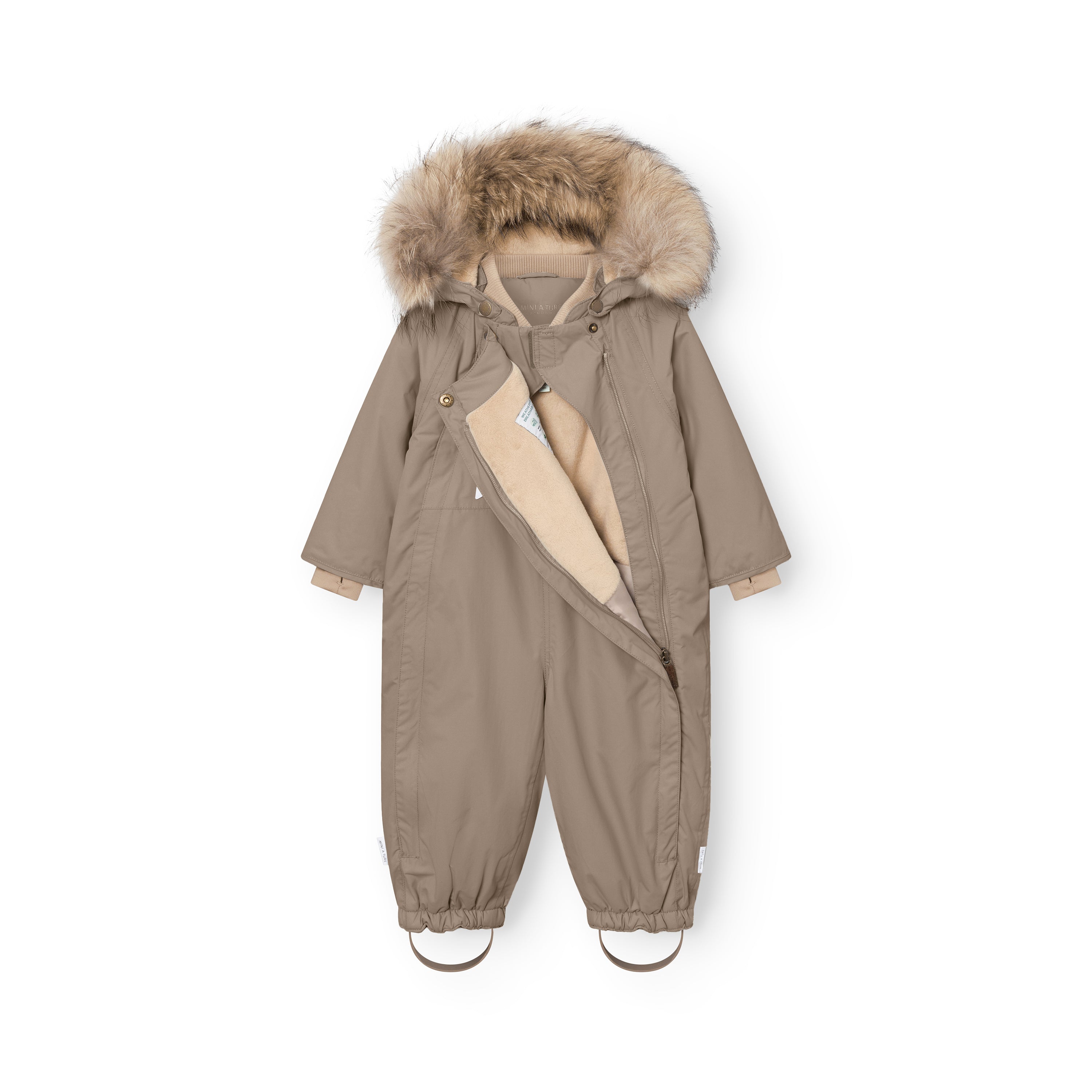 MATWISTI fleeceforet flyverdragt med pels i varm gråbrun/taupe-farve, fotograferet forfra med den ene lynlås åben, så det bløde beige fleecefór er synligt på venstre side af forsiden. Hætten er trukket op med den store, naturlige pelskant udfoldet, beige manchetter stikker frem ved håndleddene, og de rynkede bukseben med fodstropper ses ved anklerne.