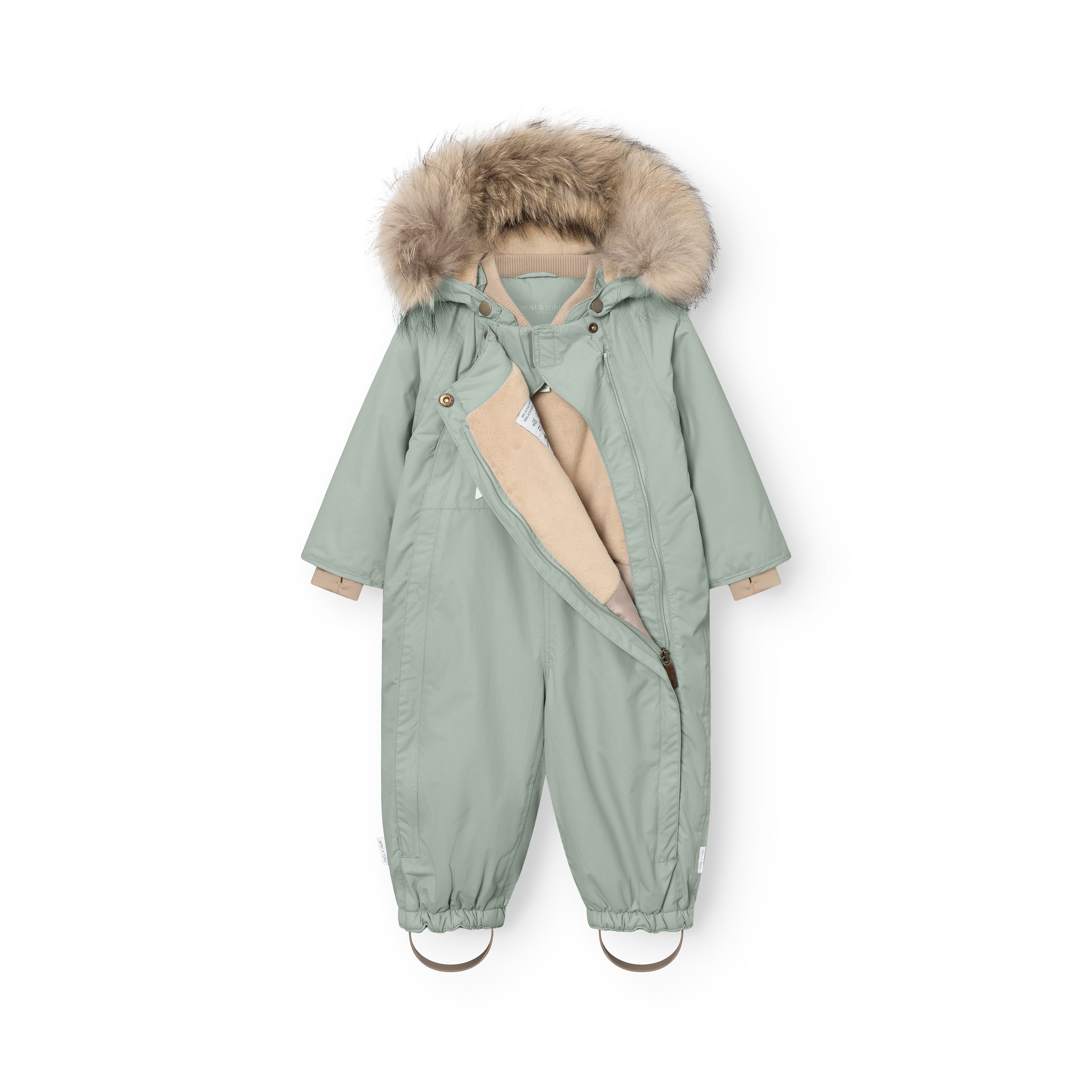 MATWISTI fleeceforet flyverdragt med pels i støvet mintgrøn, fotograferet forfra med den ene lynlås åben, så det bløde beige fleecefór er synligt på indersiden. Hætten er trukket op, og den store, naturlige pelskant er udfoldet. Der ses en beige ribkant ved halsen, og beige fodstropper hænger ned ved anklerne.