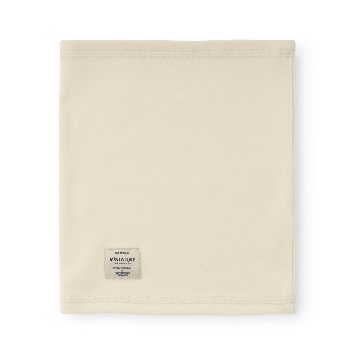 MATAKON let fleece-halsedisse til børn i farven Angora Cream, fotograferet bagfra og udfoldet fladt. MINI A TURE-mærket er synligt nederst til venstre på det jævnt farvede, cremehvide fleecemateriale.