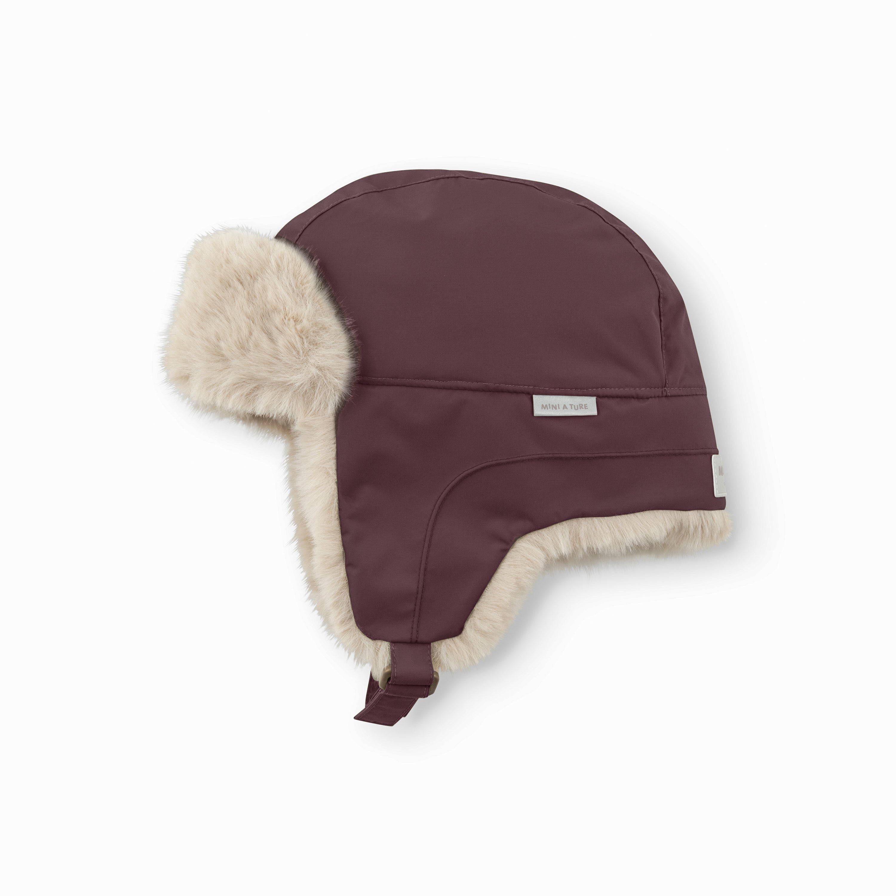 MATCRISTER teddyforet vinterhue i mørk vinrød set fra skrå vinkel, med det cremefarvede teddyfleece-for langs kanten af øreklapperne og velcrolukningen tydeligt fremhævet forneden.