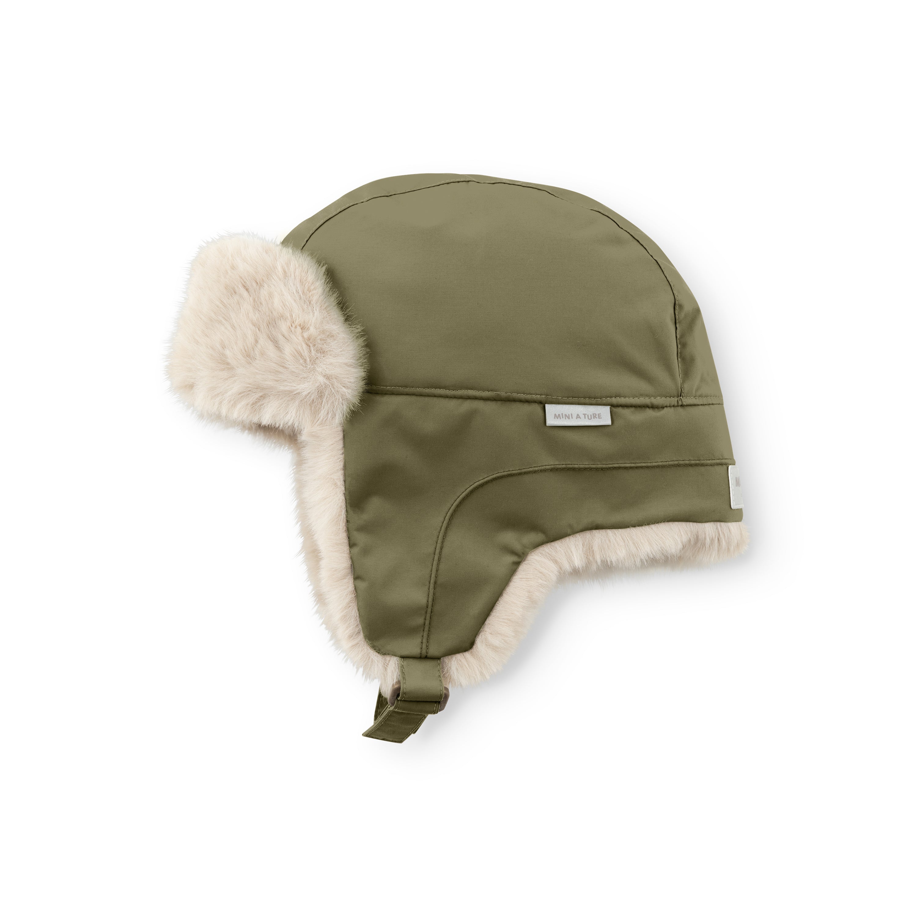 MATCRISTER teddyforet vinterhue i dæmpet olivengrøn set fra skrå side med et MINI A TURE-label på ydersiden og blødt, cremefarvet teddyfleece, der følger kanten af den brede øreklap og toppen af huen. En olivengrøn velcrostrop hænger ned langs siden.