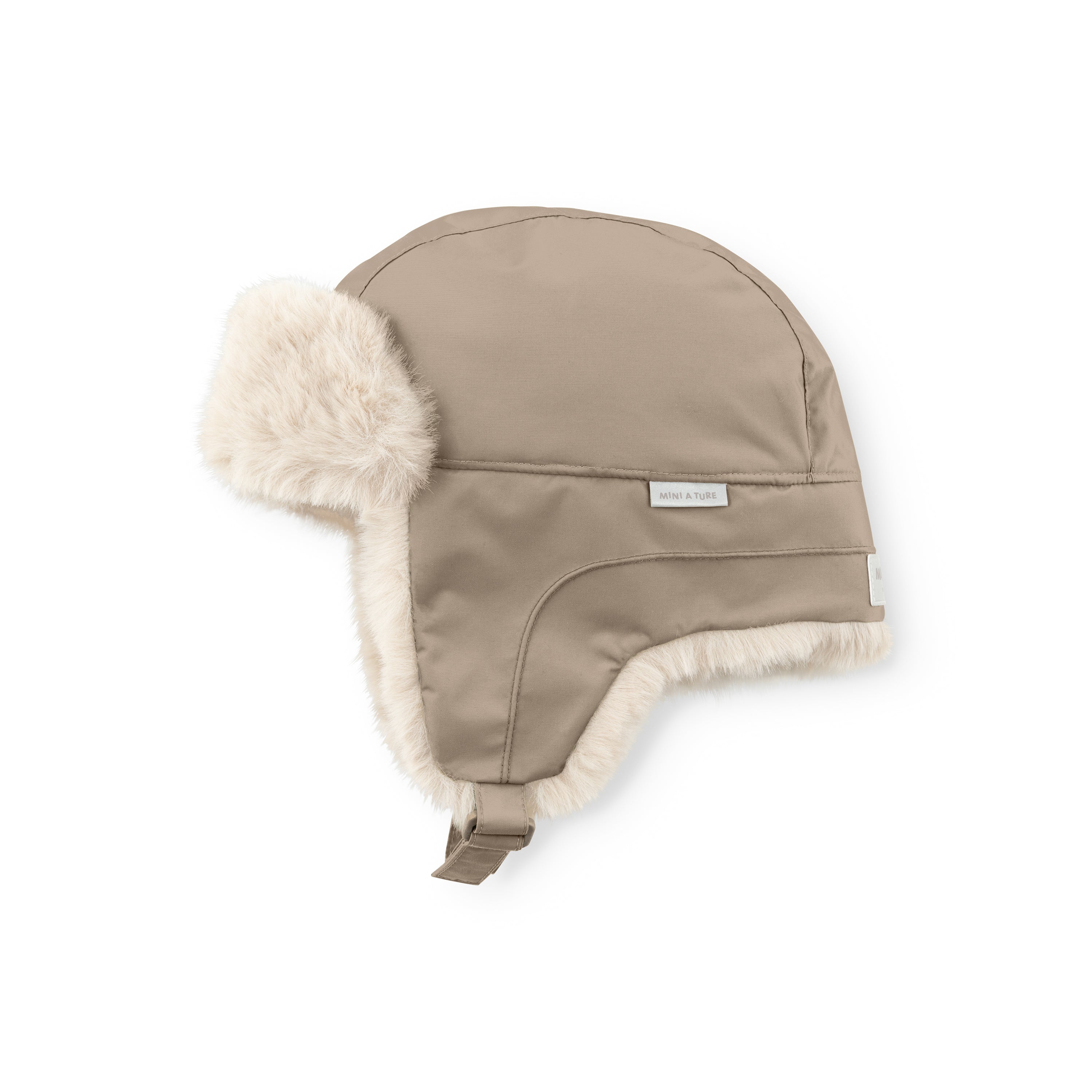 MATCRISTER teddyforet vinterhue i lys sandbeige, fotograferet fra skrå side mod hvid baggrund. Det glatte yderstof af genanvendt nylon dækker toppen og siderne af huen, mens et tykt, cremefarvet teddyfleece ses langs hele kanten af øreklapperne og på den fremstående øreklap til venstre. En matchende beige velcrostrop med metalspænde hænger ned i bunden til venstre.